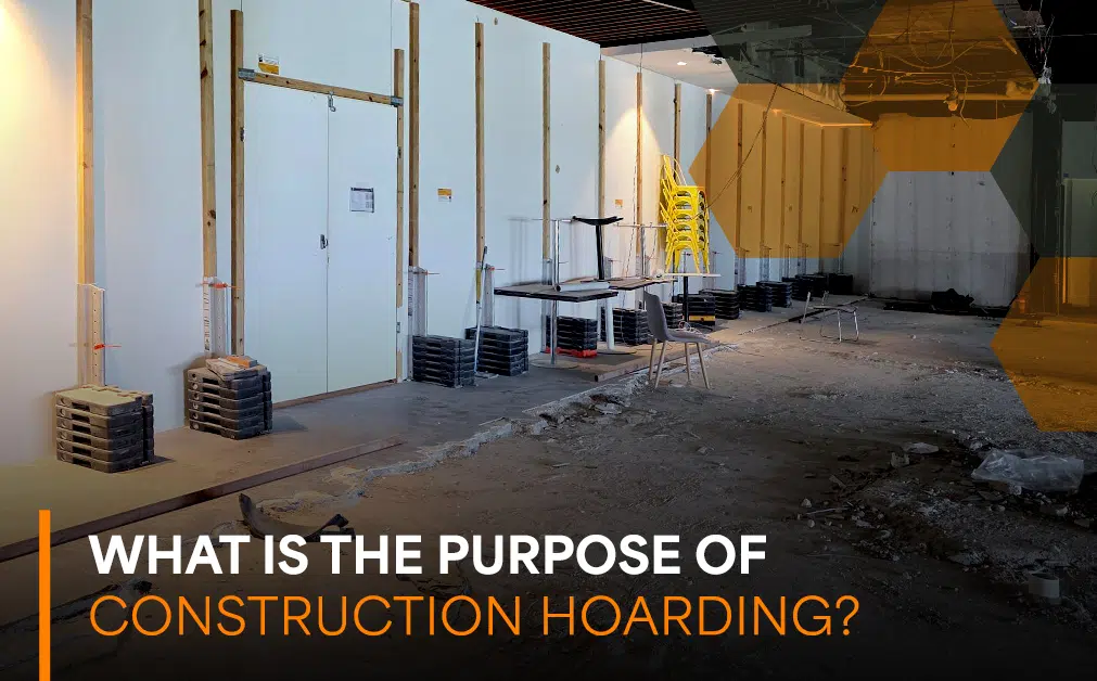 Commercial construction site with temporary hoarding walls separating building works from surrounding areas, with exposed flooring, equipment and materials. Overlaid text reads “What Is the Purpose of Construction Hoarding?”, highlighting its role in site safety, security and protecting the public during commercial construction and fitout projects.